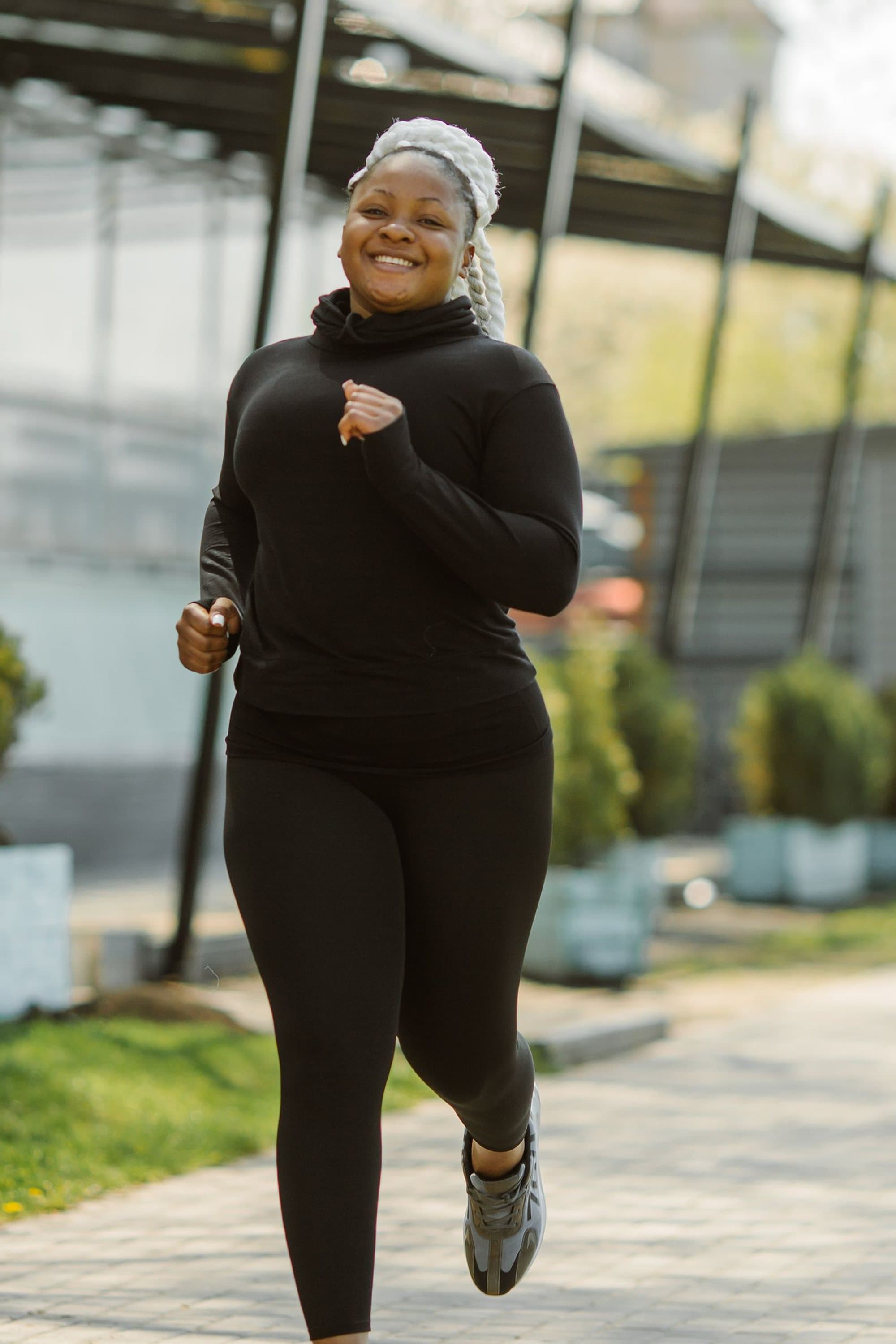 Midsize woman jogging outdoors on a sunny path